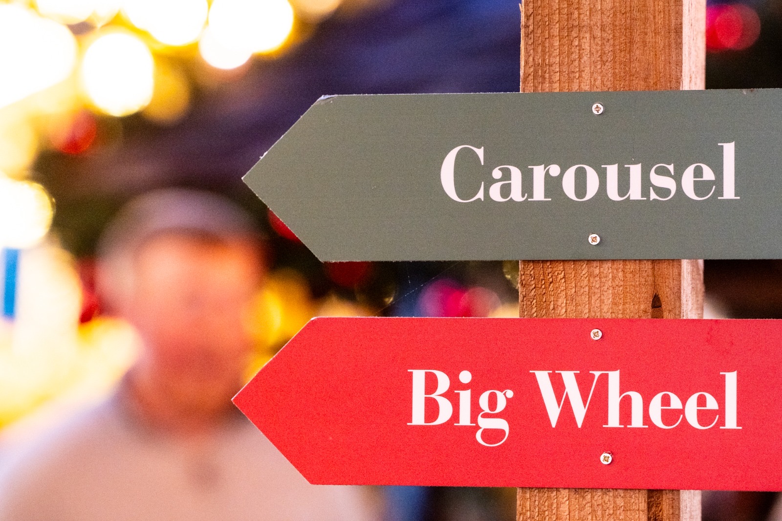 Wooden signpost pointing towards the carousel and the big wheel